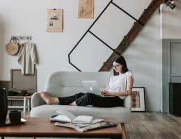 A girl lying on a couch looking at a laptop