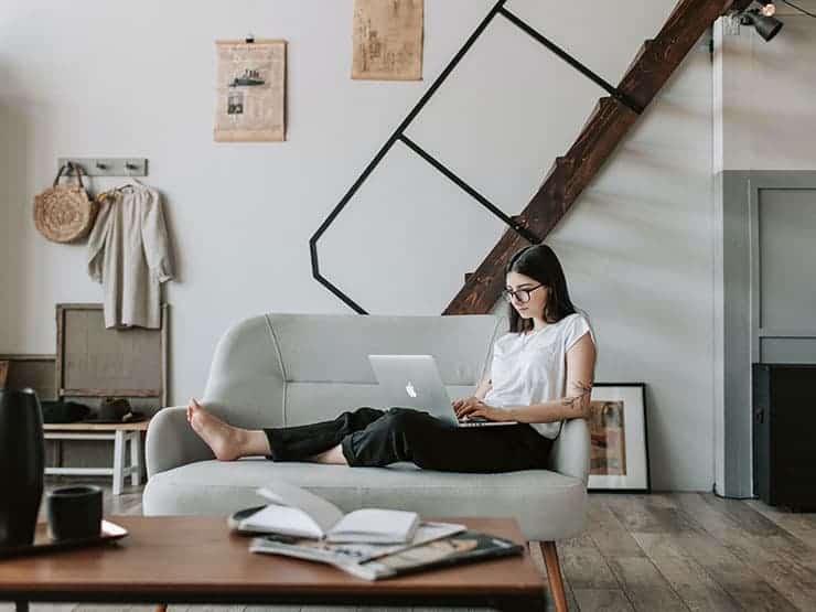 A girl lying on a couch looking at a laptop